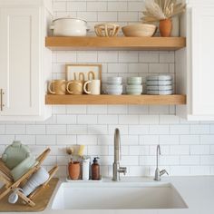 the kitchen is clean and ready to be used for cooking or baking, with dishes stacked on shelves above the sink