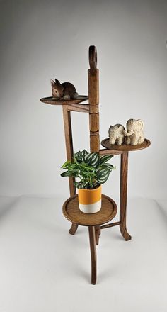 three tiered wooden shelf with potted plant and cat figurines on top