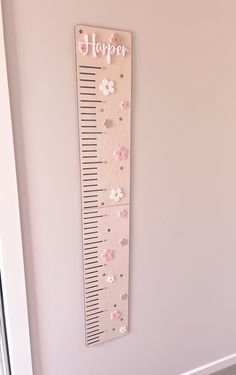 a wooden growth chart with flowers and the words happy on it hanging on a wall