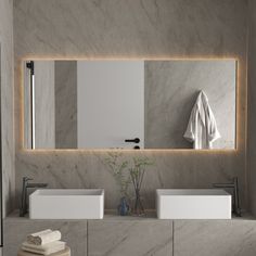 a bathroom with two sinks and a large mirror above it's countertop, along with towels on the wall