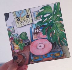 a person holding up a drawing of a plant and record player in their living room