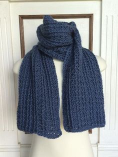 a blue knitted scarf sitting on top of a white mannequin