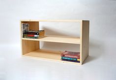 a book shelf made out of plywood with books on each shelf and magazines in the middle