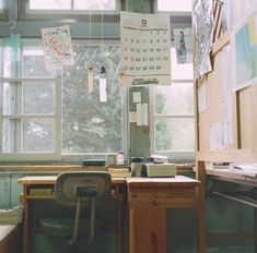 a desk and chair in an office with lots of papers hanging from the ceiling above it