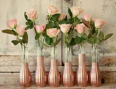 six vases with pink roses in them on a table next to a wall and a door