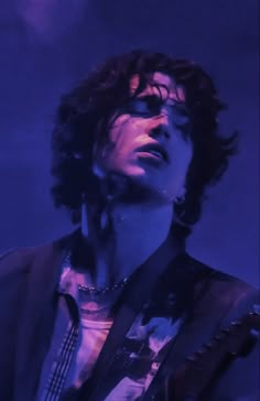 a man with curly hair and glasses holding a guitar