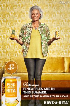 an older woman holding a can of pineapple in front of a couch with a yellow wallpaper