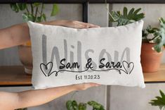 someone holding up a pillow with the names of their wedding day and date on it