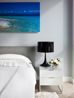 a white bed sitting next to a black lamp on top of a table in a bedroom