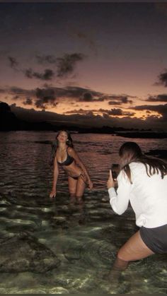 two women in the water playing with a frisbee at sunset or dawn time