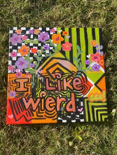 a piece of art that says i like weird on it in front of some grass