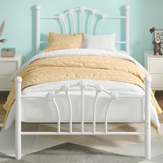 a white bed with yellow sheets and pillows in a blue walled room, next to two nightstands