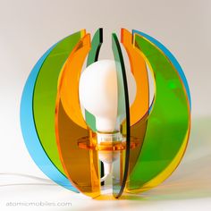 a lamp that is sitting on top of a white surface with green, orange and blue circles around it