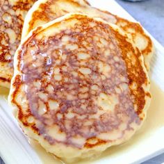 three pancakes on a white plate covered in syrup