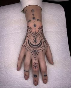 a woman's hand with tattoos on it sitting on top of a white sheet