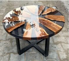 a round table made out of wood and black metal with an artistic design on the top