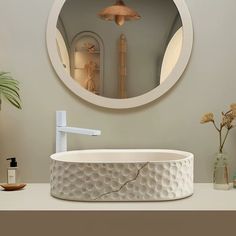 a bathroom sink with a circular mirror above it