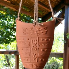 a clay pot hanging from a rope on a porch