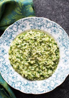 a white and blue bowl filled with broccoli on top of a green cloth