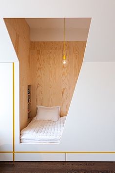 a small bed in the corner of a room with wood paneling on the walls