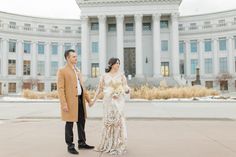 a bride and groom holding hands in front of the state capitol building on their wedding day