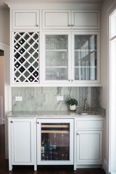 a kitchen with white cabinets and marble counter tops, wine rack on the wall above the sink