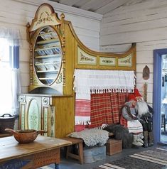 an old fashioned room with many items on the floor, including blankets and rugs