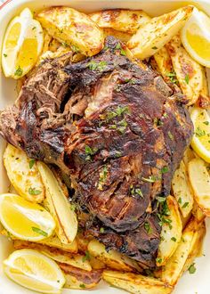 a roast beef with potatoes and lemons in a casserole dish