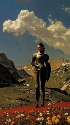 a woman standing on top of a lush green hillside next to flowers and mountains with clouds in the sky