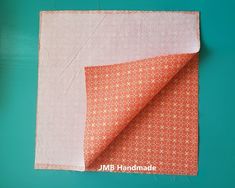 an orange and pink fabric with white dots on it, next to a piece of cloth