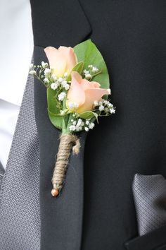 a boutonniere with pink roses and baby's breath is tied to a black suit