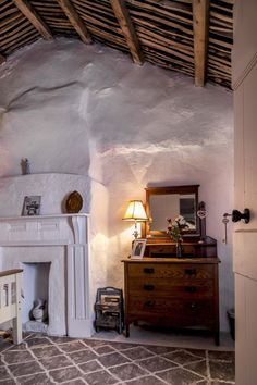 a living room with a fireplace, mirror and dresser next to a wall that has exposed wood beams