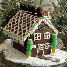 a gingerbread house is decorated with icing and decorations on a cake platter