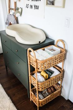 a bathroom sink sitting next to a green cabinet with baskets on it's sides