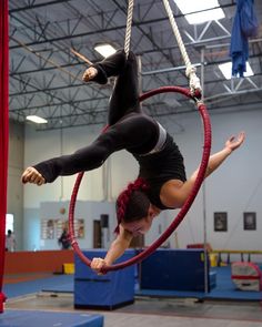 a woman is doing aerial tricks on a hoop