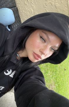 a woman wearing a black hoodie is taking a selfie