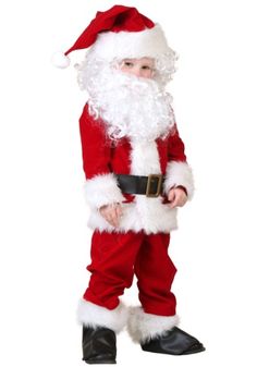 a little boy dressed up as santa claus for christmas time, standing with his hands in his pockets