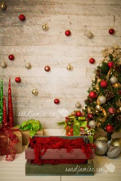 a christmas tree and presents in front of a white brick wall with ornaments on it