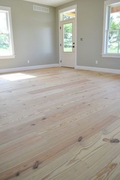 empty room with hard wood floors and two windows in the corner, looking into another room