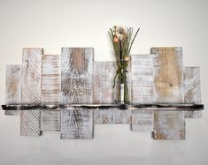 a vase filled with flowers sitting on top of a wooden shelf next to a wall