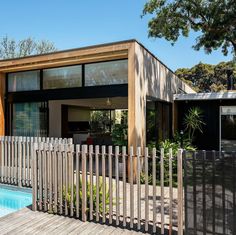 a house with a pool in front of it and a wooden fence around the yard