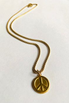 Long Peace Necklace Plated brass. Sturdy coin size charm of brass. Peace sign design. Sturdy long 22" gold over steel chain. Steel lobster clasp. Super fun to wear and layer with other necklaces. Long Peace Necklace Brass Medallion Charm Necklace With Adjustable Chain, Brass Coin Necklace With Adjustable Chain, Nickel Free Brass Medallion Necklace With Round Pendant, Nickel-free Brass Charm Necklace With Round Pendant, Gold-tone Brass Charm Necklace With Round Pendant, Nickel-free Brass Medallion Necklace With Round Pendant, Brass Round Pendant Charm Necklace, Brass Medallion Charm Necklaces, Symbolic Coin-shaped Brass Necklaces