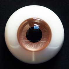 an eyeball is sitting on a black surface with its reflection in the glass lens