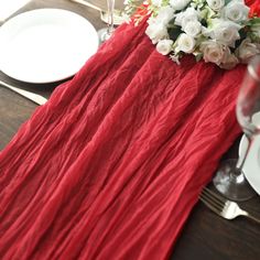 the table is set with white and red flowers, silverware, and wine glasses