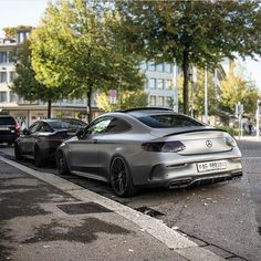 two cars parked next to each other on the side of the road in front of some buildings