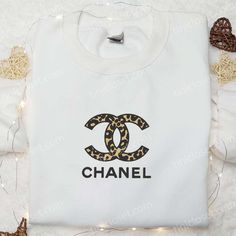 Introducing the Leopard Chanel Logo Embroidered Shirt, a true fashion staple that combines elegance and fierceness. Made from high-quality materials, this shirt showcases a stunning leopard print with the iconic Chanel logo embroidered on the front. With its comfortable fit and trendy design, it effortlessly adds a touch of luxury to any outfit. Stand out from the crowd and express your unique sense of style with this eye-catching shirt. Elevate your streetwear game with our Brand Logo Embroider Chanel Logo Aesthetic, Chanel Hoodie, Chanel Sweatshirt, Chanel Sweater, Chanel Top, Exude Confidence, Best Gifts For Mom, Chanel Logo, The Leopard