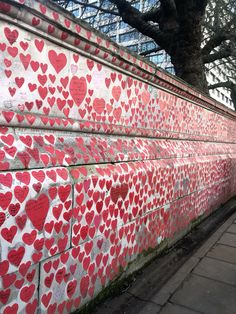 a wall with hearts painted on it next to a tree