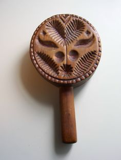 a carved wooden object on a white surface with a wood stick sticking out of it