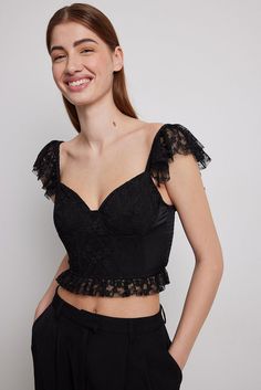 This top is made of lace and satin and features underwired cups, a corset design, frilled shoulder straps in lace, a smocked back and a frilled bottom hem edge in lace. Lace Tops With Spaghetti Straps And Ruffles, Lace Top With Ruffles And Spaghetti Straps, Lace Tops With Ruffles And Spaghetti Straps, Black Corset With Lace Trim And Sweetheart Neckline, Fitted Lace Camisole With Ruffles, Lace Closure Top For Summer Parties, Ruffled Lace Camisole, Fitted Lace Trim Camisole With Ruffled Straps, Fitted Camisole With Lace Trim And Ruffled Straps