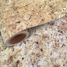 a roll of brown and white marble paper on top of a granite countertop next to a sink